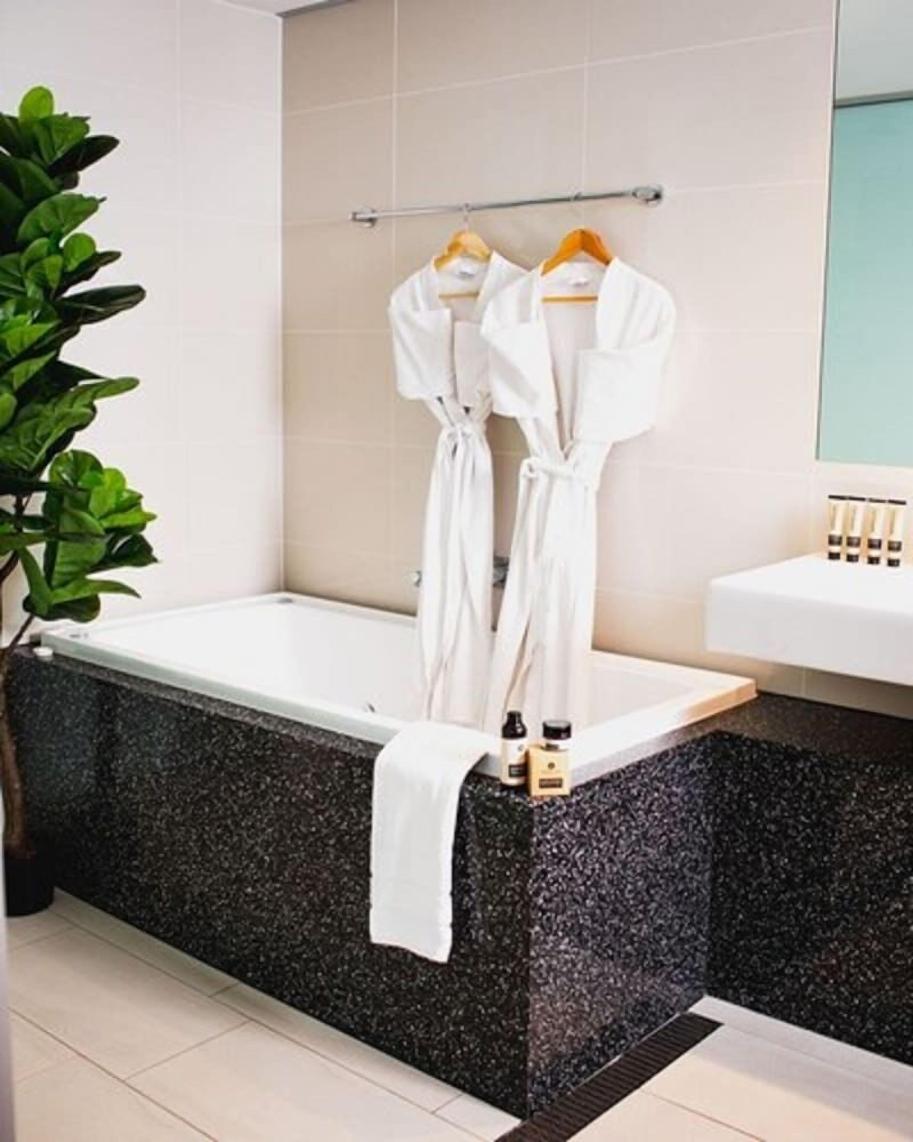 A bathroom with a bathtub, a towel, and a plant.