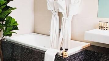 A bathroom with a bathtub, a towel, and a plant.