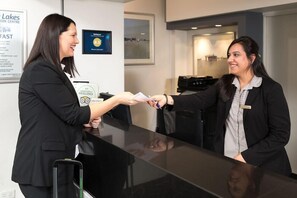 Dos personas intercambiando documentos en la recepción de un hotel.
