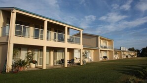 Un motel à plusieurs étages, doté d’un toit plat, de grandes fenêtres et d’une pelouse verdoyante.