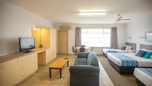 Une chambre d’hôtel équipée d’une télévision, d’un canapé, d’un lit, d’un bureau et d’une fenêtre avec des rideaux.