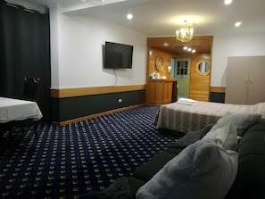 A hotel room with a bed, a sofa, a TV, a desk, and a wardrobe. - Ascot Motor Inn (Sydney)