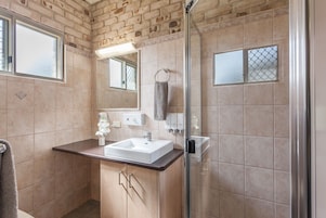 Un baño con ducha de vidrio, lavamanos blanco y espejo.