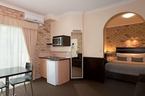 A compact hotel room with a kitchenette, a bed, and a small dining area. - Highlander Motor Inn (Toowoomba)