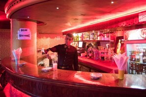 Un espace bar avec un comptoir, des bouteilles et un distributeur de billets.
