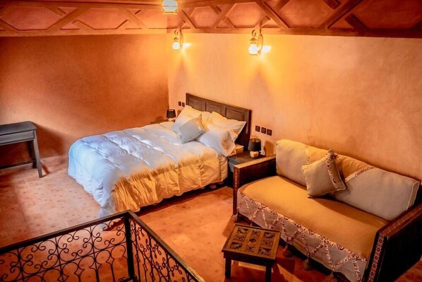A cozy bedroom with a bed, a sofa, and a nightstand. - Ecolodge Ouednoujoum (Ouarzazate)