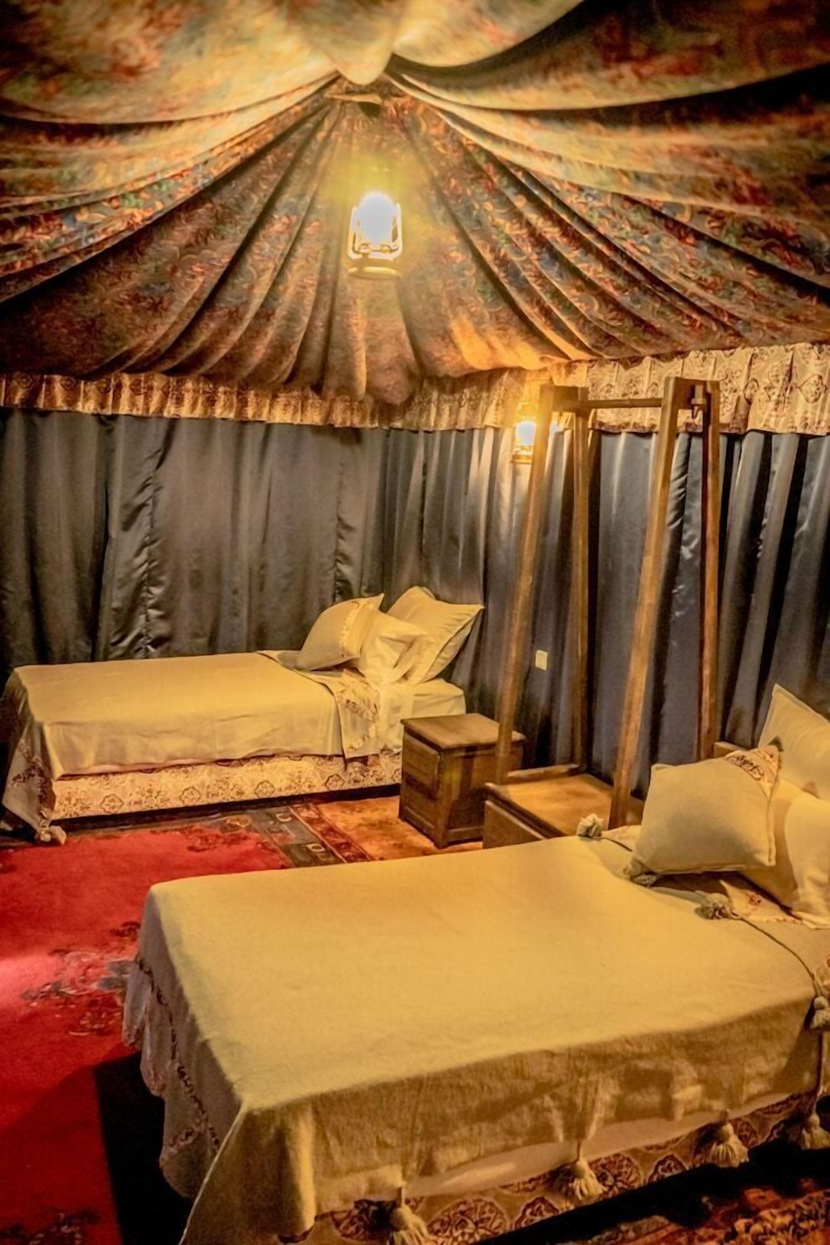 Una habitación con dos camas, una mesita y un espejo.