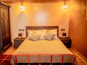 Una cama bien hecha con dos almohadas, un cabecero de madera y dos lámparas de noche.