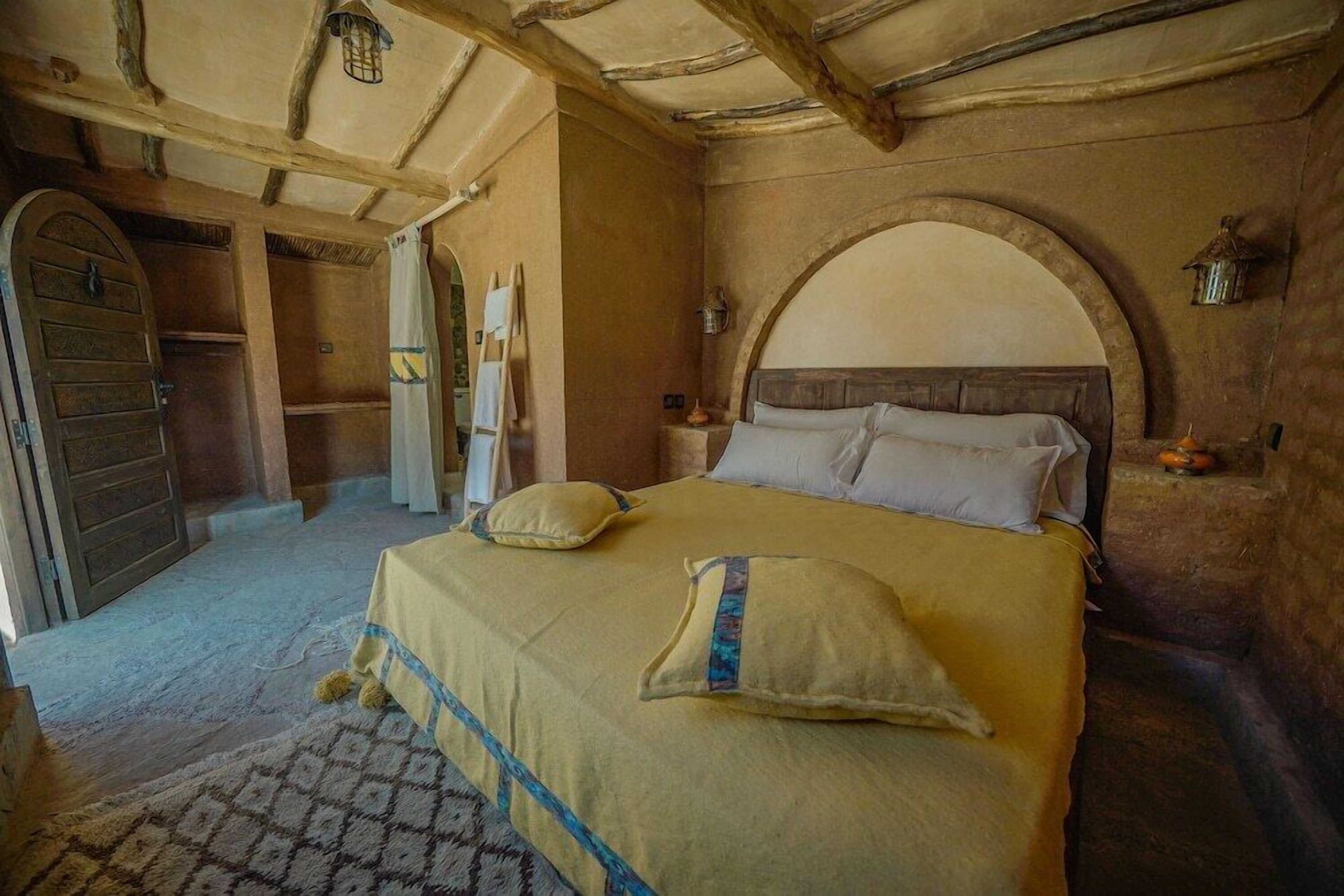 Een klassieke kamer met een bed, houten balken en een stenen muur.