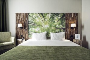 A hotel room with a large bed, two bedside lamps, a green patterned chair, and a wall with a nature-themed mural. - Best Western Plus Hotel Atlant (Genk)