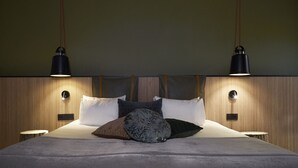A modern bedroom with a wooden headboard, two bedside lamps, and a variety of pillows. - Best Western Plus Hotel Atlant (Genk)
