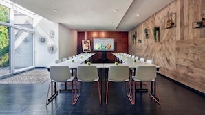 A modern conference room with a long table, white chairs, a large screen, and wooden paneling. - Best Western Plus Hotel Atlant (Genk)