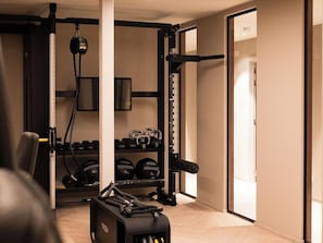 A gym with weightlifting equipment, a squat rack, and dumbbells. - Hotel Restaurant Verviers (Verviers)