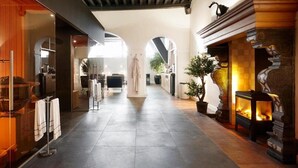 A spacious corridor with a fireplace, arched windows, and a modern interior design. - Grand Hotel De Draak And Residence Dagmara (Bergen op Zoom)
