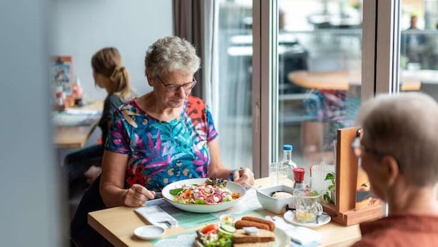 Un coin repas avec une table dressée pour deux personnes, comprenant un repas et un verre d’eau.