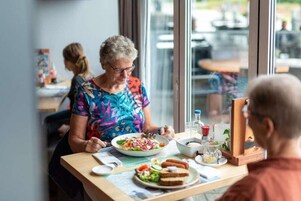 Comedor con una mesa dispuesta para dos personas, mostrando una comida y un vaso de agua.