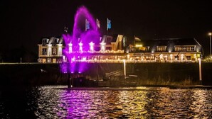 Un hôtel situé au bord de l’eau, doté d’une fontaine remarquable et d’une façade illuminée.