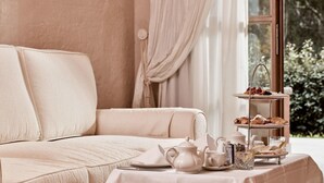 A room with a beige sofa, a three-tiered tea service, and a window with curtains. - La Villa Del Re - Adults Only (Castiadas)