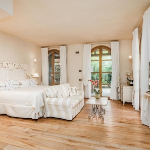 A hotel room with a bed, a sofa, a small table, and a window with curtains. - La Villa Del Re - Adults Only (Castiadas)