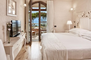 A bedroom with a large bed, a television on a dresser, and a view of the outdoors through a glass door. - La Villa Del Re - Adults Only (Castiadas)