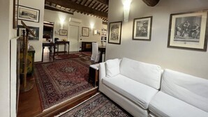 Une pièce avec un canapé blanc, une moquette rouge à motifs et des œuvres d’art encadrées accrochées aux murs.