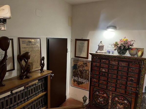 A room with a wooden cabinet, a framed poster, and a wall-mounted light fixture. - A Casa Di Paola Suite (Ravenna)