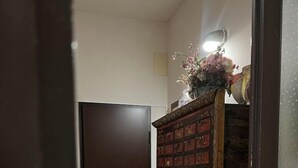 Un couloir avec une armoire en bois, une porte et un sol carrelé.