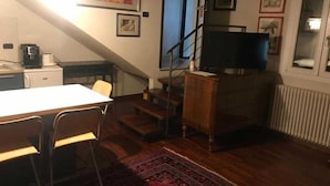 Un espace de vie compact comprenant un coin repas, un escalier et un téléviseur.