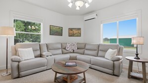 A living room with a beige sectional sofa, a round coffee table, and two side tables. - Relax at Stephens Legacy Farmhouse, a spacious 4BR retreat with valley and mountain views (Dayton)