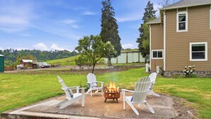 A backyard with a fire pit and white Adirondack chairs. - Relax at Stephens Legacy Farmhouse, a spacious 4BR retreat with valley and mountain views (Dayton)