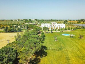 A large, white building with a swimming pool, surrounded by well-maintained lawns and trees. - Tenuta La Baronessa (Tuglie)