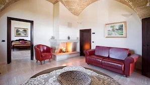 Amplia sala de estar con chimenea, sofá de cuero rojo y alfombra estampada.