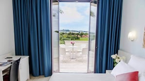 Una habitación de hotel con cama, escritorio y vista a un patio exterior con sillas y mesa.