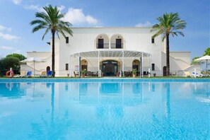A hotel with a swimming pool, palm trees, and a covered outdoor seating area. - Tenuta La Baronessa (Tuglie)