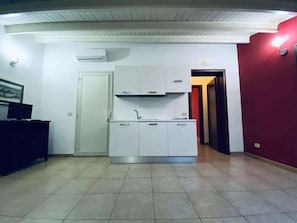 Une cuisine de taille réduite avec des meubles blancs, un four encastré et un sol carrelé.