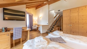 A bedroom with a bed, a desk, a chair, a TV, and a wardrobe. - Alp Holiday Dolomiti (Dimaro Folgarida)