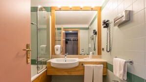 A compact bathroom with a glass shower enclosure, two sinks, a mirror, and a hairdryer on the wall. - Alp Holiday Dolomiti (Dimaro Folgarida)