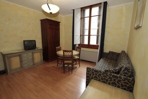Una habitación con una mesa de comedor de madera, sillas, un sofá, un televisor y un armario.