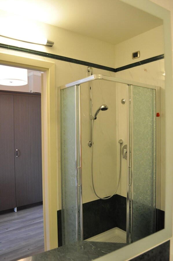 A glass-enclosed shower stall with a handheld showerhead and a wall-mounted faucet. - Residence La Repubblica & Piazza Della Repubblica, 4 (Florence)