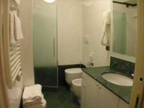 Un baño con inodoro, lavamanos, ducha y toallero.