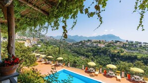 A poolside area with lounge chairs and umbrellas, overlooking a mountainous landscape. - Albergo La Margherita (Scala)