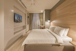 Habitación de hotel con una cama grande, un escritorio, una silla, un ventilador de techo y un cuadro en la pared.