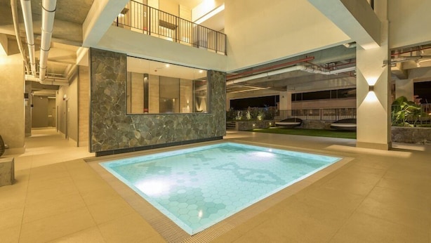 A spacious indoor swimming pool with a hexagonal tile pattern, surrounded by a tiled floor and a stone wall.