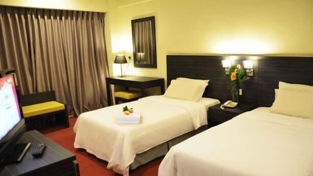 A hotel room with two beds, a desk, a chair, a TV, and a window with curtains. - Hotel Imperial (Kuala Lumpur)