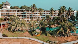 Un hotel con diversi piani, area piscina e palme.