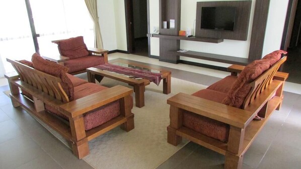A living room with wooden furniture, a flat-screen TV, and a large window. - Felda Residence Hot Springs (Ipoh)