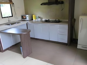 A kitchen with white cabinets, a countertop, a toaster, a stove, and a refrigerator.