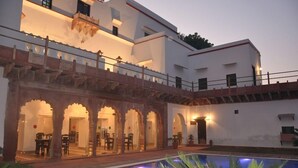 A building with a pool, arched walkways, and outdoor seating areas. - Amritara Chandra Mahal Haveli Bharatpur (Nadbai)