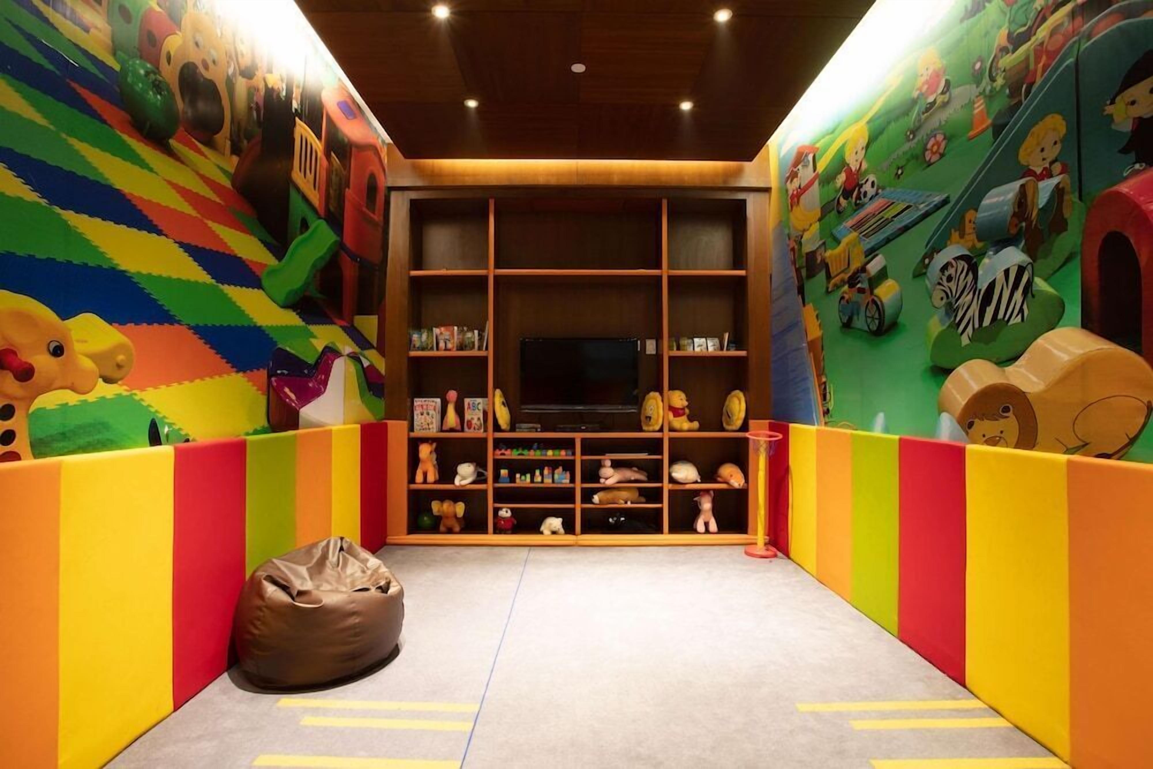 A playroom with colorful walls, a bean bag, and shelves with toys and books.