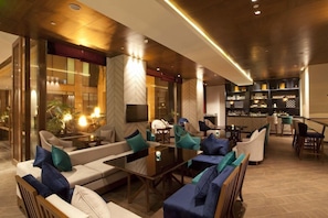 Uma área de lounge moderna com sofás, cadeiras e um bar.